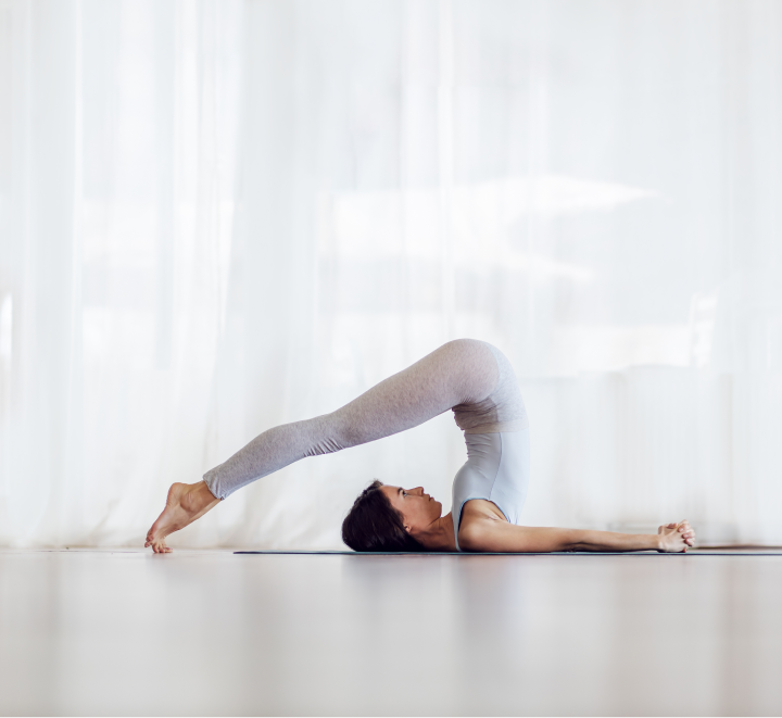 Femme en posture de la charrue pendant une séance de Vinyasa Yoga